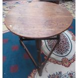 A George III oak cricket table the circular top on turned supports joined by low stretchers,