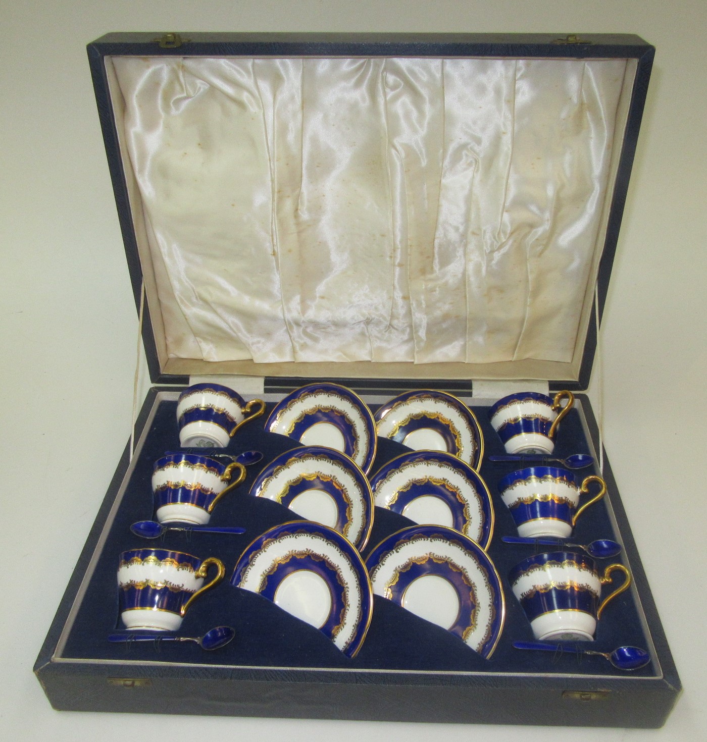 A cased set of six Aynsley porcelain cups and saucers, with six silver and blue enamelled spoons,