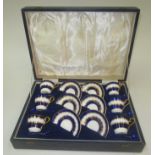 A cased set of six Aynsley porcelain cups and saucers, with six silver and blue enamelled spoons,