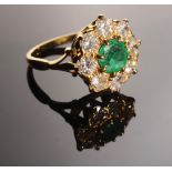 A good gold ring set with an emerald and diamond flower head cluster.