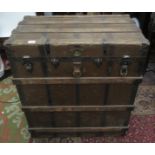 A large canvas covered and metal bound wooden trunk, with a pair of leather carrying handles,