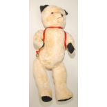 A pale plush short haired teddy bear wood wool stuffing, black pads and ears,