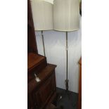 A pair of brass standard lamps each with three down swept supports and scroll feet,