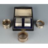 A pair of engine turned silver napkin rings cased and three other silver napkin rings. 3oz.