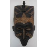 A souvenir tribal wall mask, the head mounted with a kneeling drummer, the whole with carved lines,