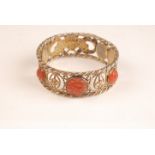 A Chinese silver gilt bangle with three carved carnelian cabochons and pierced with bats and fish.