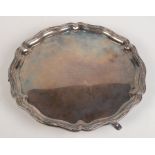 A George V silver shaped tray with a serpentine line and bead border on three legs,