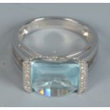 A contemporary 18ct white gold ring set a novelty cut topaz flanked by rows of diamonds.