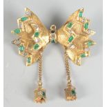 A gold brooch in the form of a bow set with emeralds and diamonds.