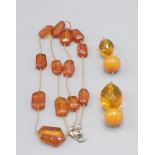Two amber beads, each strung with a faceted glass bead, together with an 'amber' bead necklace.