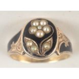 An early Victorian gold and black enamel mourning ring with a pearl set flowering plant, dated 1866,