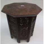 An Indian carved wood occasional table, the octagonal table on a leaf carved folding base,