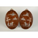 A pair of Chinese hardwood silver inlaid oval wall plaques, 20th century, decorated with a pagoda,