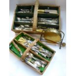 A collection of plated flatware in two cane cutlery trays and a brass gong.