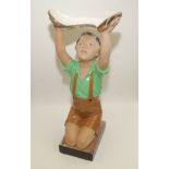 A 1930s plaster model of a kneeling boy wearing a green shirt and shorts with his arms aloft