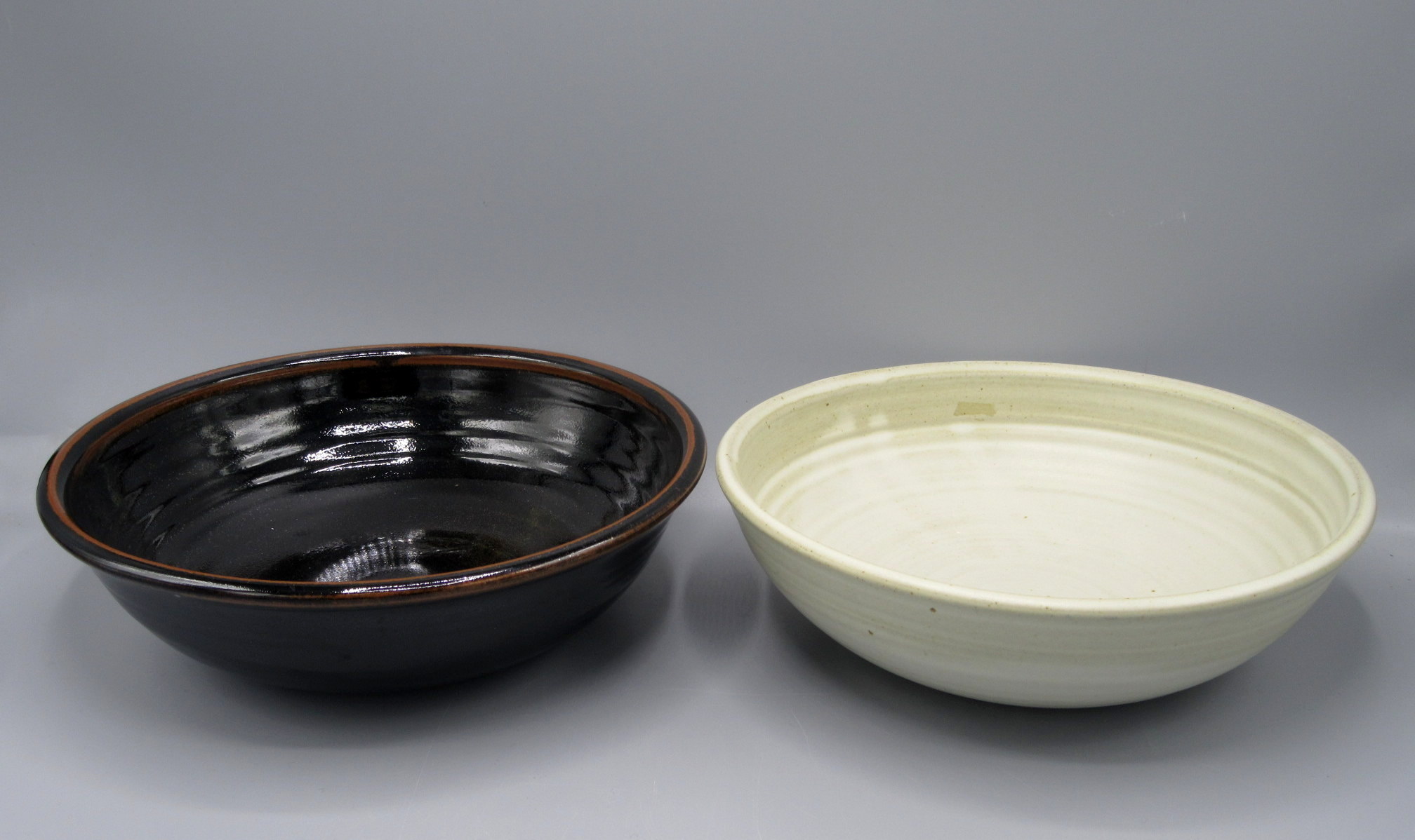 A Winchcombe Pottery bowl, with tenmoku glaze, diameter 27cm and a cream ground bowl, diameter 26.