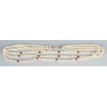 A triple strand pearl necklace spaced with garnets and gold beads.