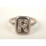An 18ct white gold ring with a diamond set initial 'R', 4.6g.