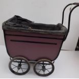 A 1930s wood and leather cloth dolls pram, with storage well, metal wheels, wood and steel handle,