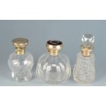 Three cut glass toilet bottles with silver mounts.