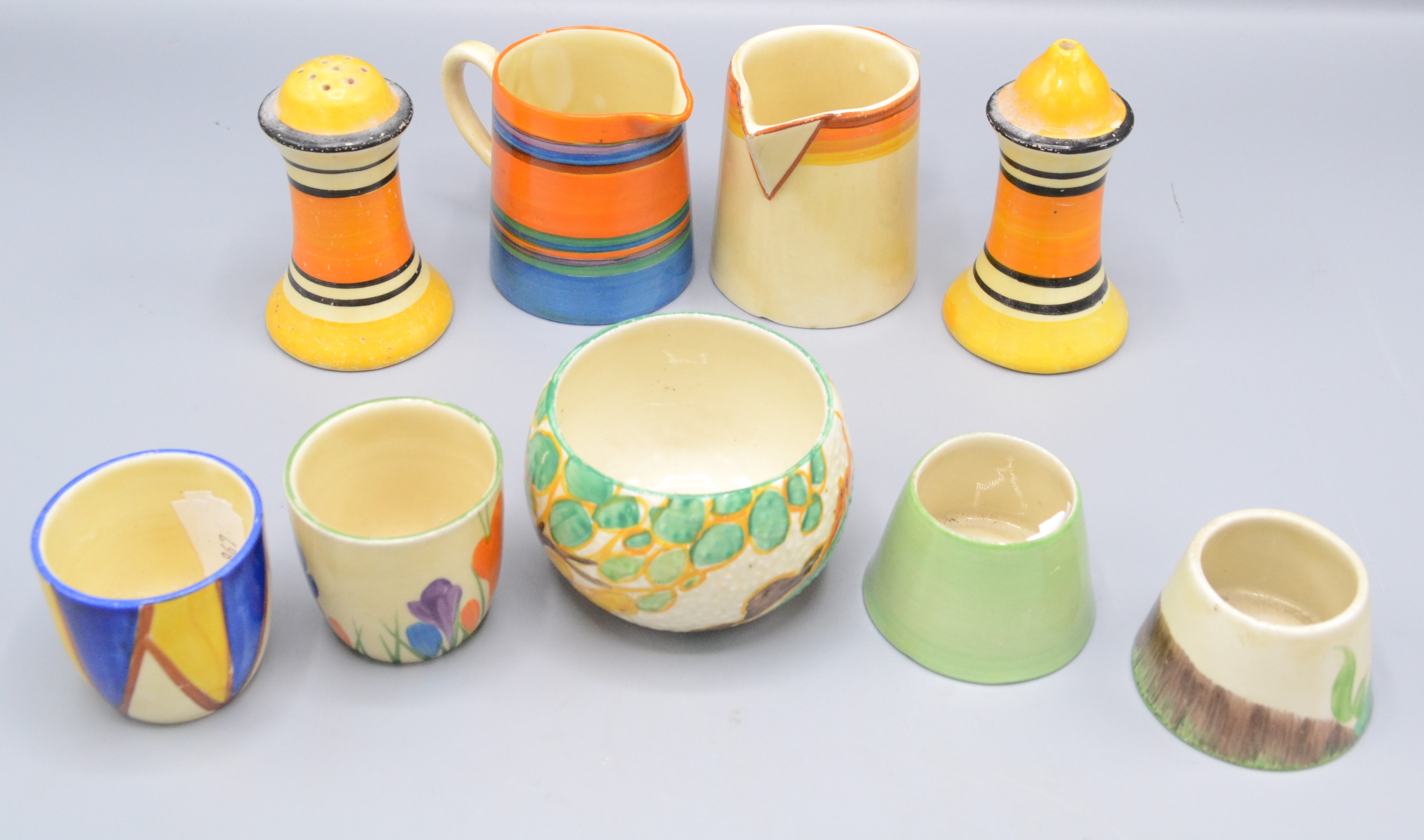 A pair of Clarice Cliff salt and pepper pots, height 8.5cm, two cream jugs and four egg cups.