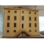 A large wood Georgian style dolls house. The front opens to reveal many rooms.
