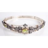A 14ct gold and silver hinged bangle set with peridot and diamonds.