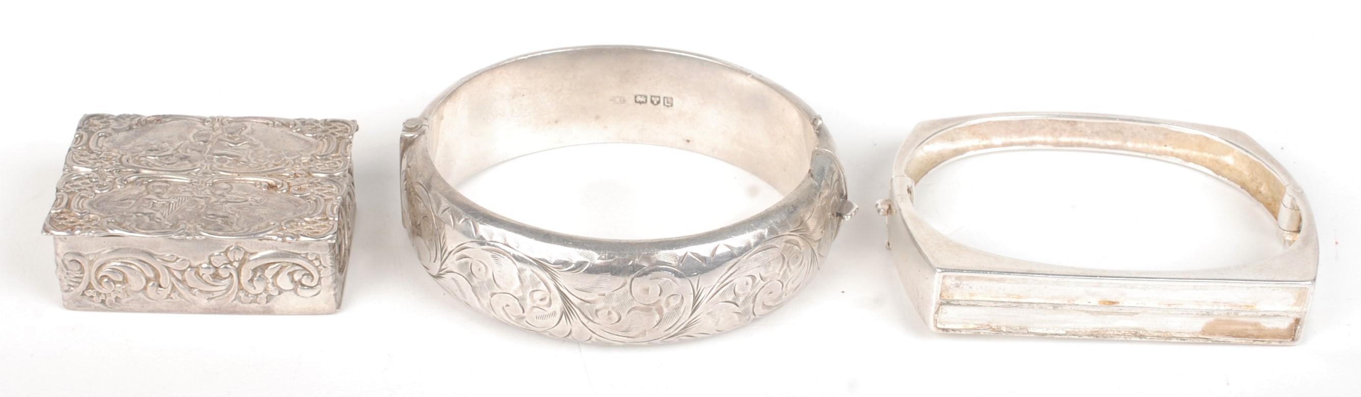 Two silver bangles and a modern silver pill box.