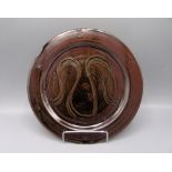 A Ray Finch Winchcombe Pottery plate, with a brown and black mottled ground and abstract design,