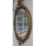 A gilt oval wall mirror, 19th century, decorated with fruit and leaves, height 126cm, width 68cm.