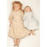 Two composition shoulder plate dolls each with fabric torso and composition legs and arms,