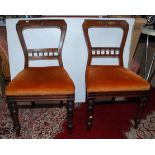 A set of four Victorian carved walnut dining chairs, each with a padded seat and on turned legs.