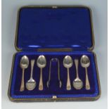 A set of six silver coffee spoons (one odd) and sugar tongs, cased. 2.8oz.