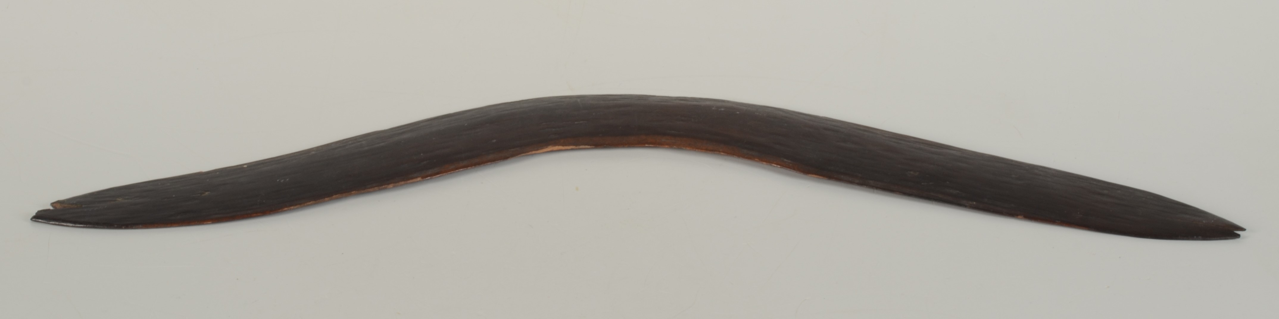 An Australian Aborigine boomerang of plain curved form, width 62cm.