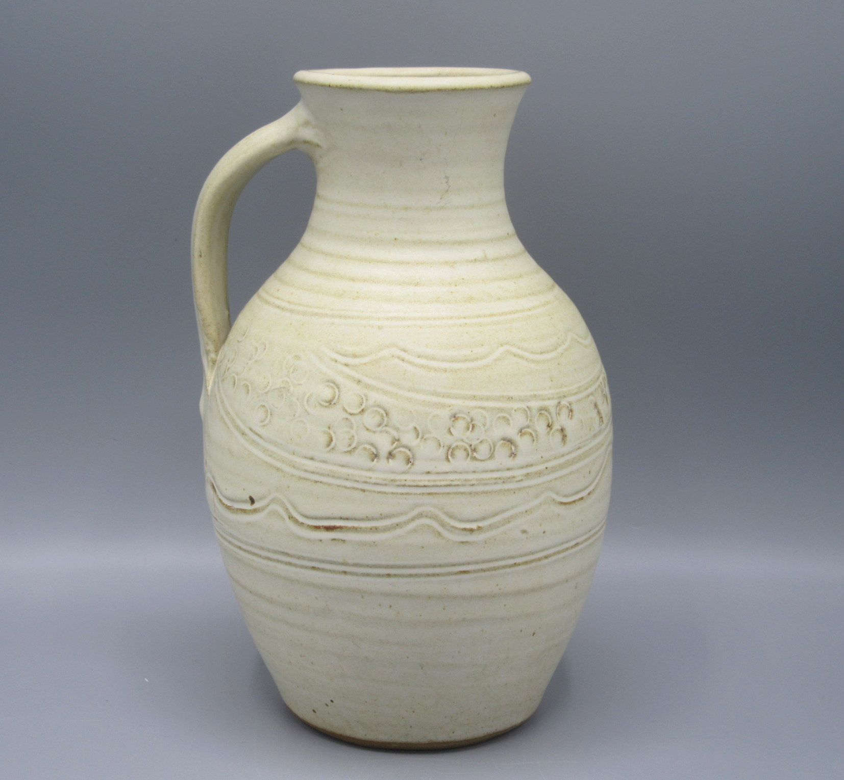 A Ray Finch Winchcombe Pottery jug, with a cream ground and abstract designs, height 24cm.