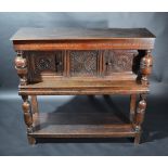 A 17th century oak joined standing livery cupboard with a pair of square panelled doors carved with