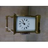 A brass carriage timepiece, white enamelled dial with black Roman Numerals, 14cm high with handle