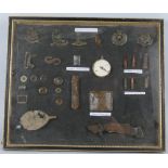 A frame display of metal detector WWI Battlefield finds, including buckles, badges, bullets,