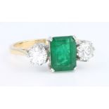 An 18ct yellow gold emerald and diamond 3 stone ring, the rectangular emerald 1.25ct flanked by