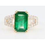 An 18ct yellow gold emerald and diamond ring, the centre stone approx. 3.2ct surrounded by baguettes