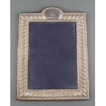 A repousse silver photograph frame with vacant cartouche 10"