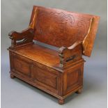 A carved oak monks bench with lion arms, the base of panelled construction and raised on bun feet