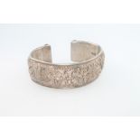 A Chinese silver bangle decorated with dragons and flowers, 57 grams