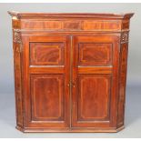 A 19th Century inlaid mahogany hanging corner cabinet with moulded cornice, enclosed by panelled