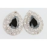 A pair of 18ct white gold treated black pear shaped diamond earrings, the centre stones 7ct