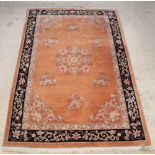 An orange and floral patterned Chinese rug with central medallion, some signs of old moth 112" x 72"