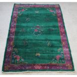 A 1930's green and purple ground floral patterned Chinese rug 101" x 73"There is some moth and
