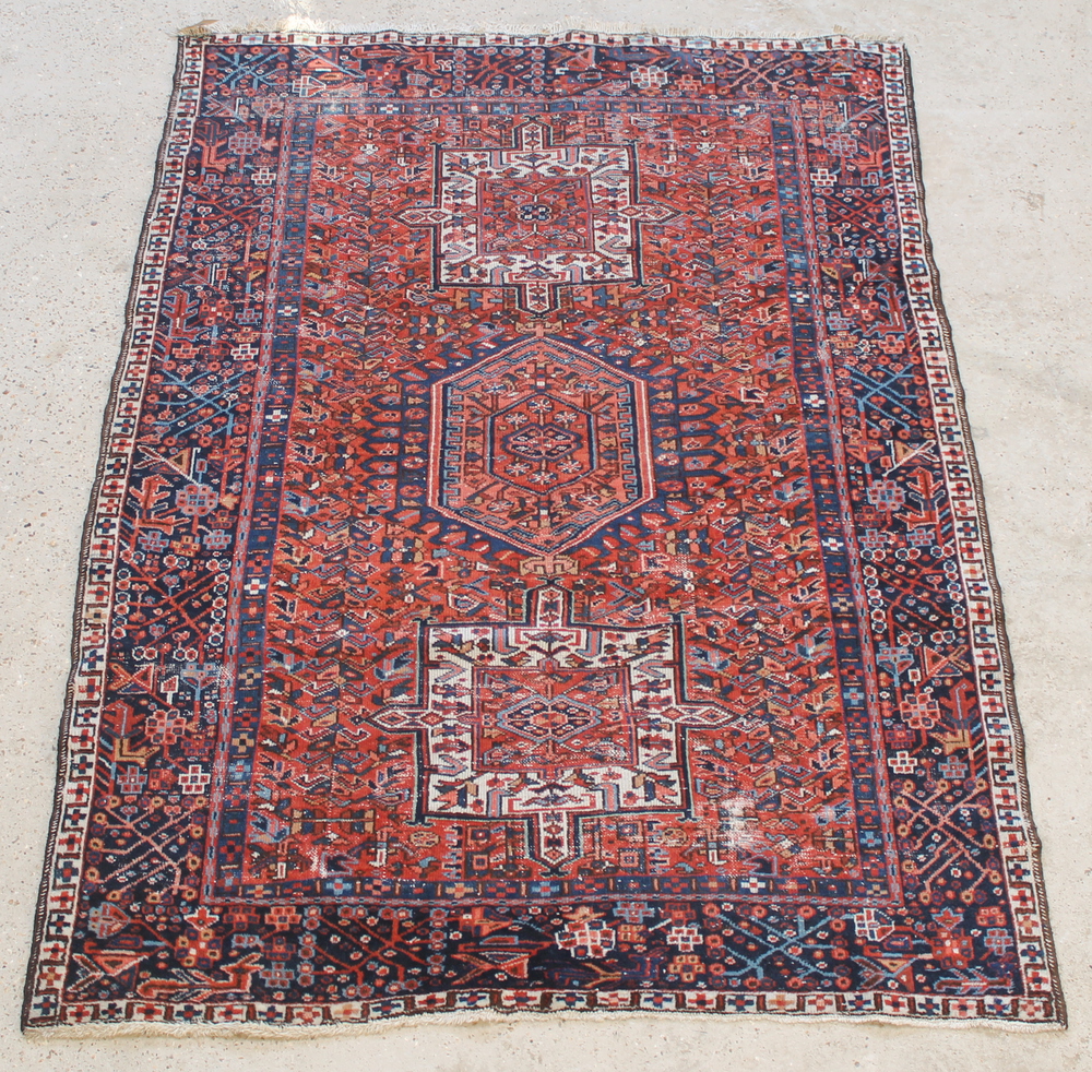 A blue and red ground Persian Heriz rug with stylised diamond to the centre supported by 2 square