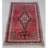 A red and white ground Persian Behbahan rug with central medallion 89" x 53"There is some wear