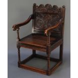 A Victorian oak open arm chair with carved panelled back and solid seat, raised on turned and